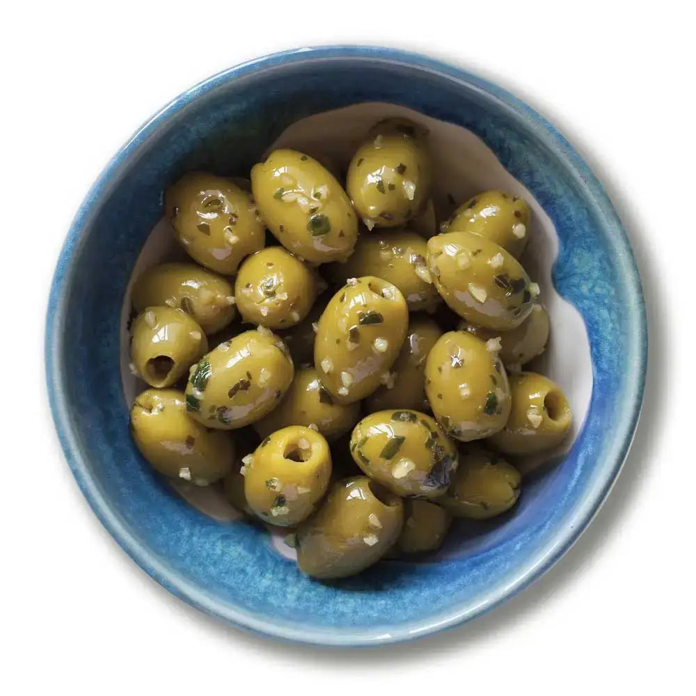 A bowl of organic wild garlic and basil pitted green olives speckled with herbs and garlic flakes perfect for snacking