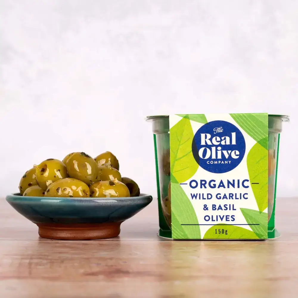 A vibrant green and white 150g container of organic wild garlic and basil pitted green olives from the real olive company