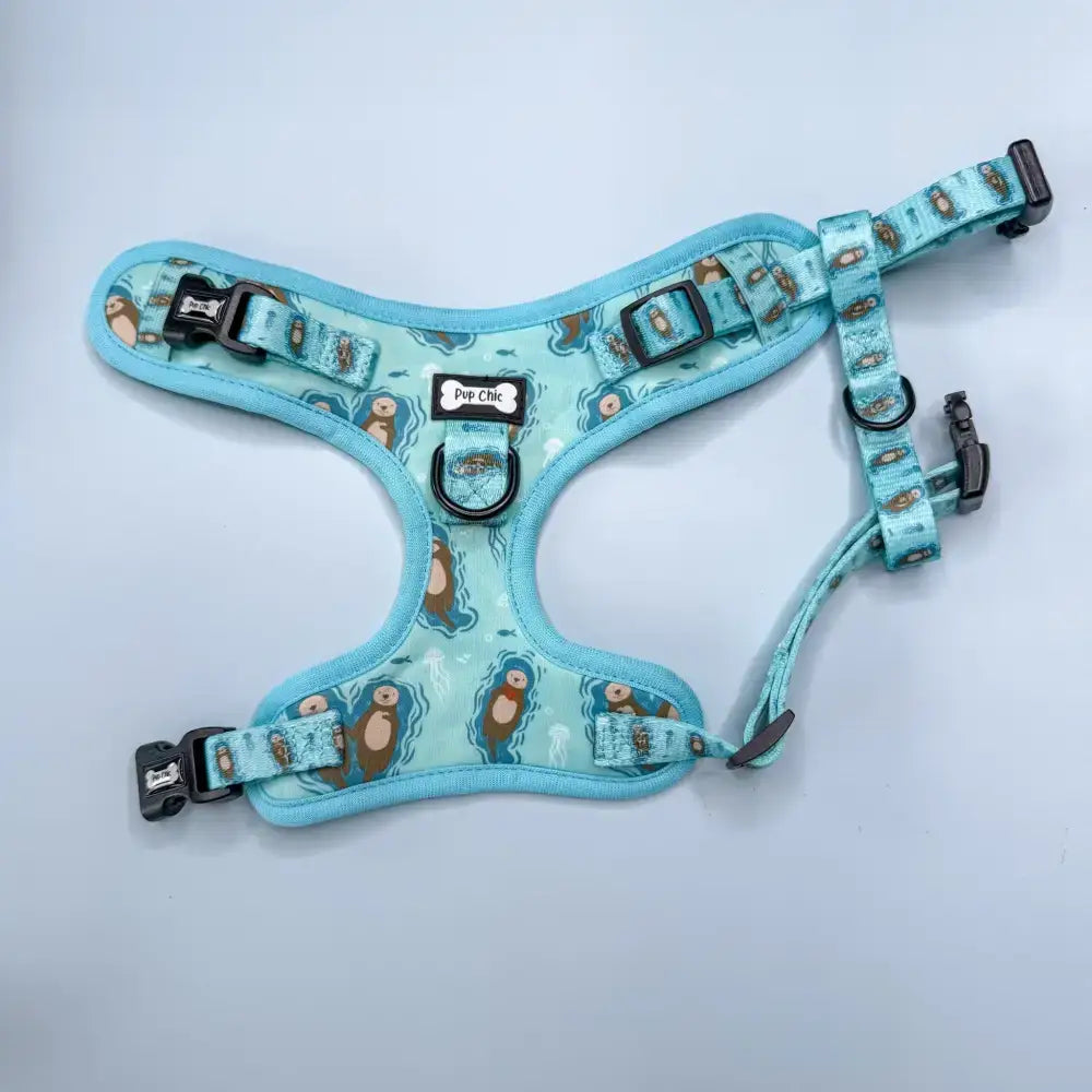A light blue otterly lovely step-in dog harness with sea otter print and black plastic buckles for pup chic style