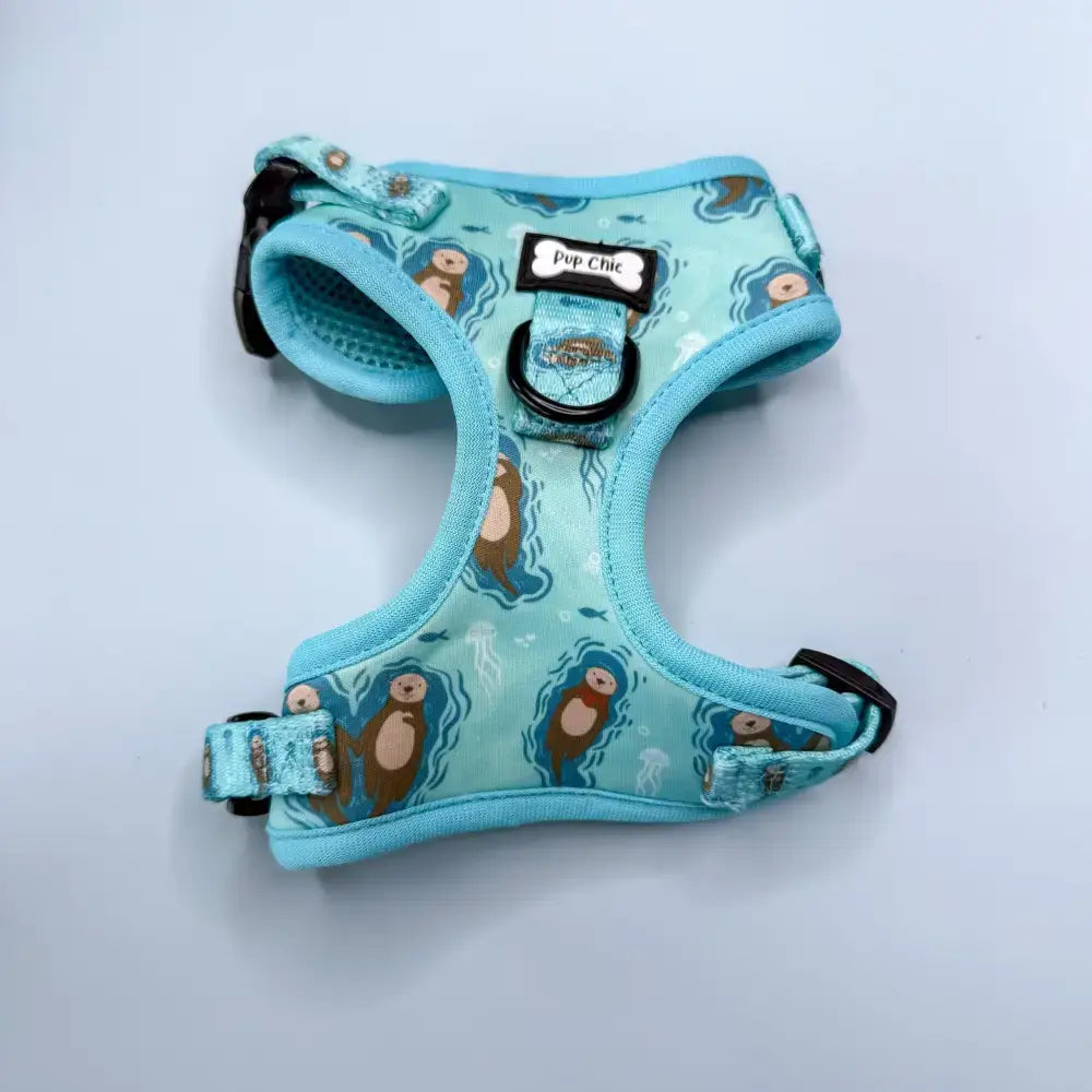 A light blue otterly lovely step-in dog harness with sea otter print, black hardware, adjustable straps for pup chic style