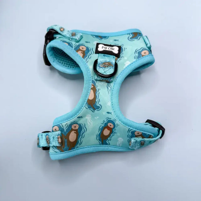 A light blue otterly lovely step-in dog harness with sea otter print, black hardware, adjustable straps for pup chic style