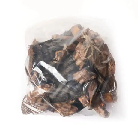 A clear plastic bag of dark brown and black dried forest mushrooms labeled paddock farm hairy cow ears