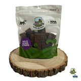 A clear plastic bag of dark brown paddock farm strips wild boar dog treats with a green and white label