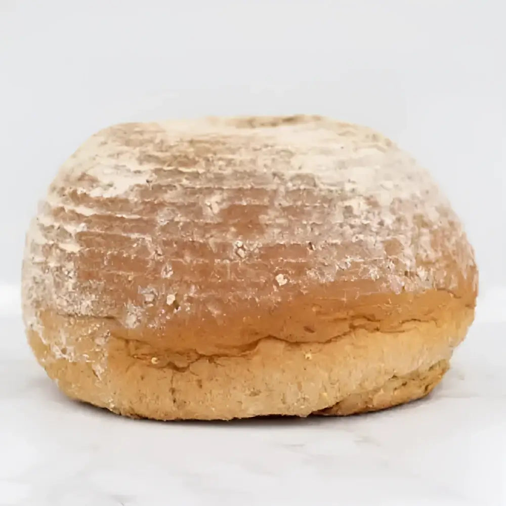 A rustic round pantique bread loaf with golden brown crust lightly dusted in flour perfect for white bread lovers