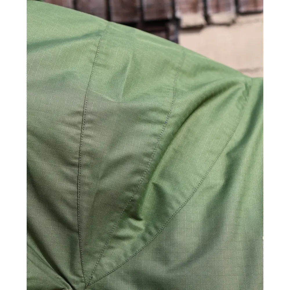 Close-up of a green textured perf combo 0g lightweight turnout rug showing visible stitching on the fabric seams