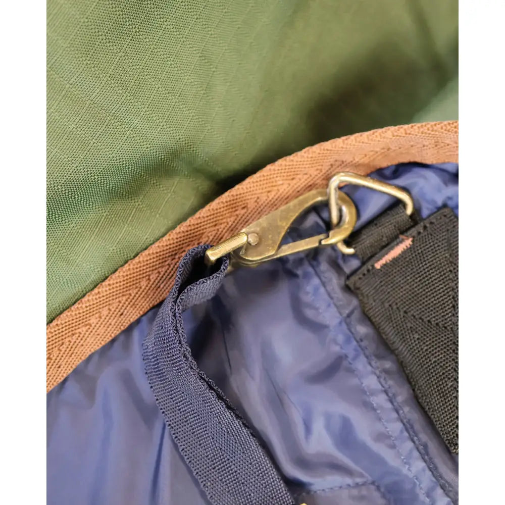 Bronze metal carabiner attached to blue nylon strap and olive green edge on lightweight turnout rug standard 0g