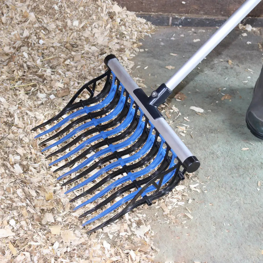 Blue and black plastic tines on silver metal handle of perry equestrian camel stable fork for efficient wood chip collection