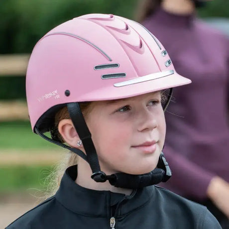 Pink equestrian helmet with silver accents and black straps.