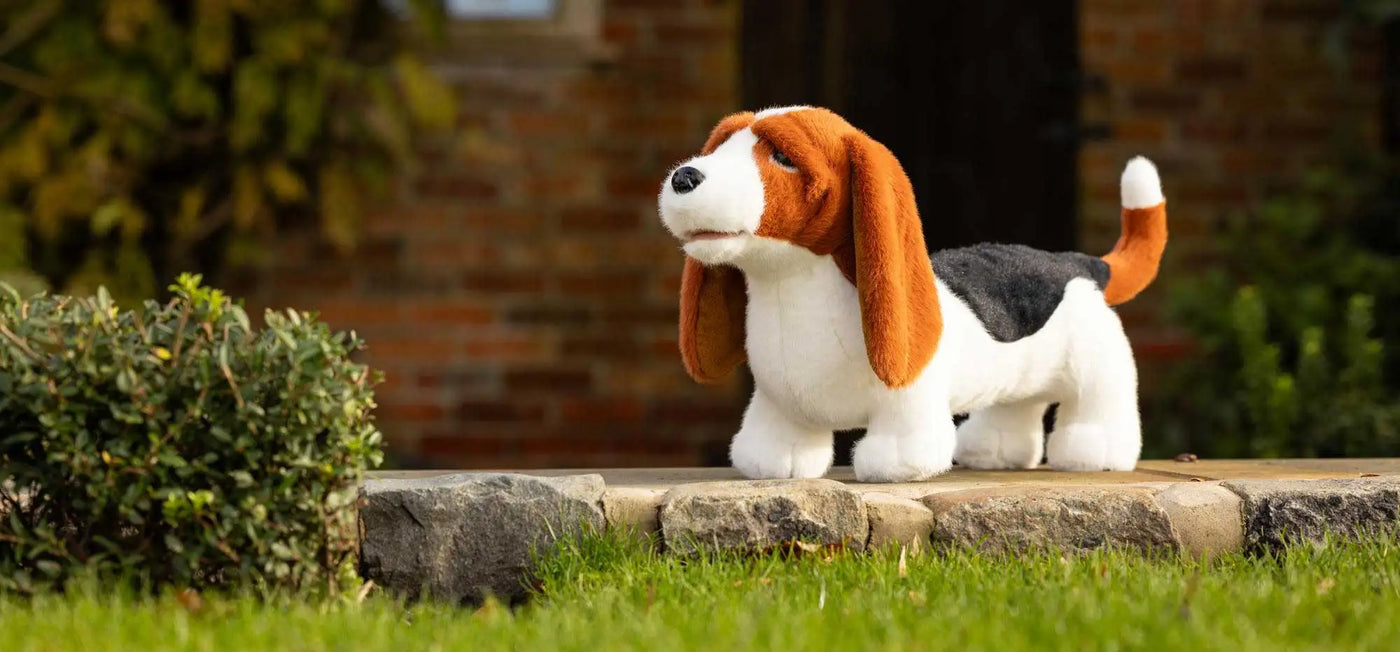 A plush beagle toy with long brown ears, a white body, and black patch on its back.