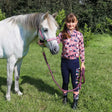 White pony with pink halter beside girl in patterned shirt, featuring Pony Passion head collar