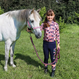 White pony with pink halter beside girl in patterned shirt, featuring Pony Passion head collar