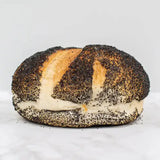 A golden-brown poppy seed cob loaf with a crust of black seeds and a soft white interior of round white bread