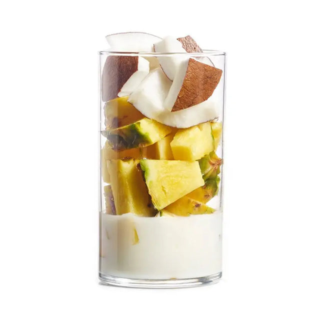A clear glass cup of projuice coconut crush smoothie with white yogurt, yellow pineapple, and brown coconut pieces