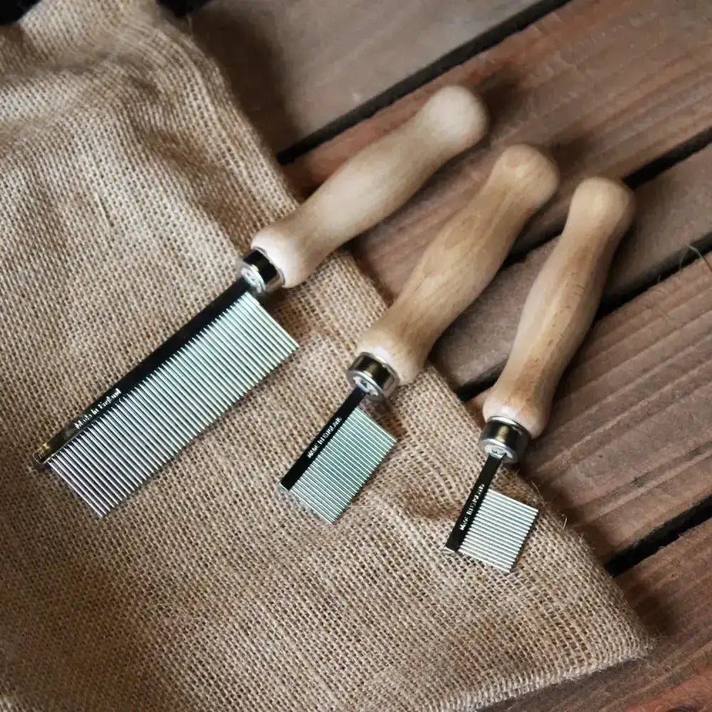 Three wooden-handled metal pet dander combs in varying sizes for smart grooming quarter and quarter marking comb use
