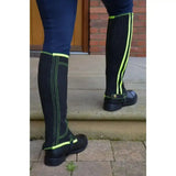 Black reflector half chaps with neon green stripes, ribbed texture, and adjustable strap closure by hy equestrian