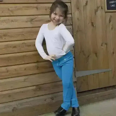 A young girl wearing bright blue rhinegold childs jodhpurs essential everyday with inside pocket and black boots