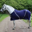 A navy blue rhinegold comfey fleece rug with white trim and black buckles made from anti-pill material fits snug on horse