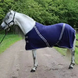 A navy blue rhinegold comfey fleece rug with white trim and black buckles made from anti-pill material fits snug on horse