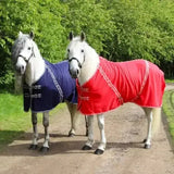 Two white horses wearing rhinegold comfey fleece rugs in navy blue and red made with soft anti-pill material