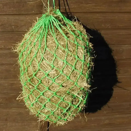 Green mesh hay net filled with golden straw hanging on wood background from rhinegold horsehage nets