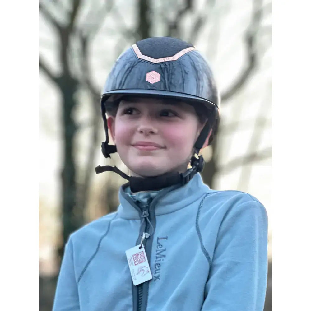 Dark blue equestrian helmet with pink trim and hexagonal logo featuring rider emergency tag for emergency contacts and medical details