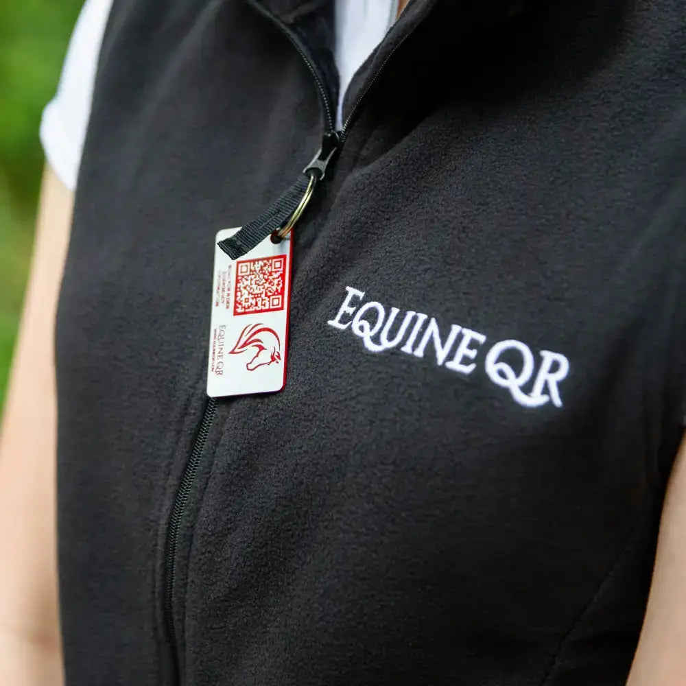 Black fleece rider emergency tag vest with white equine qr embroidery and red and white emergency contacts tag on zipper