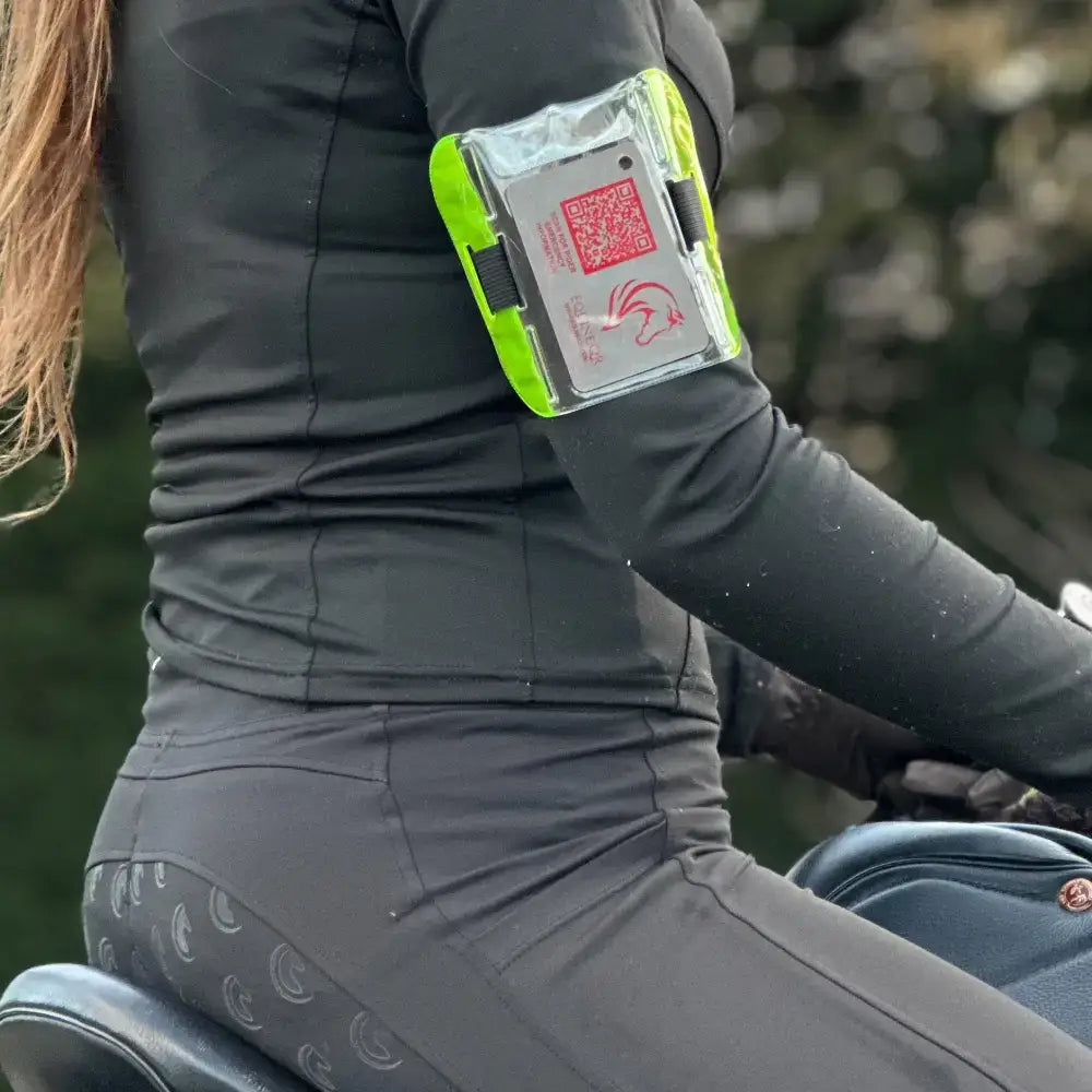 Vibrant neon green rider emergency tag armband with clear plastic front and black straps to hold emergency contacts and medical details