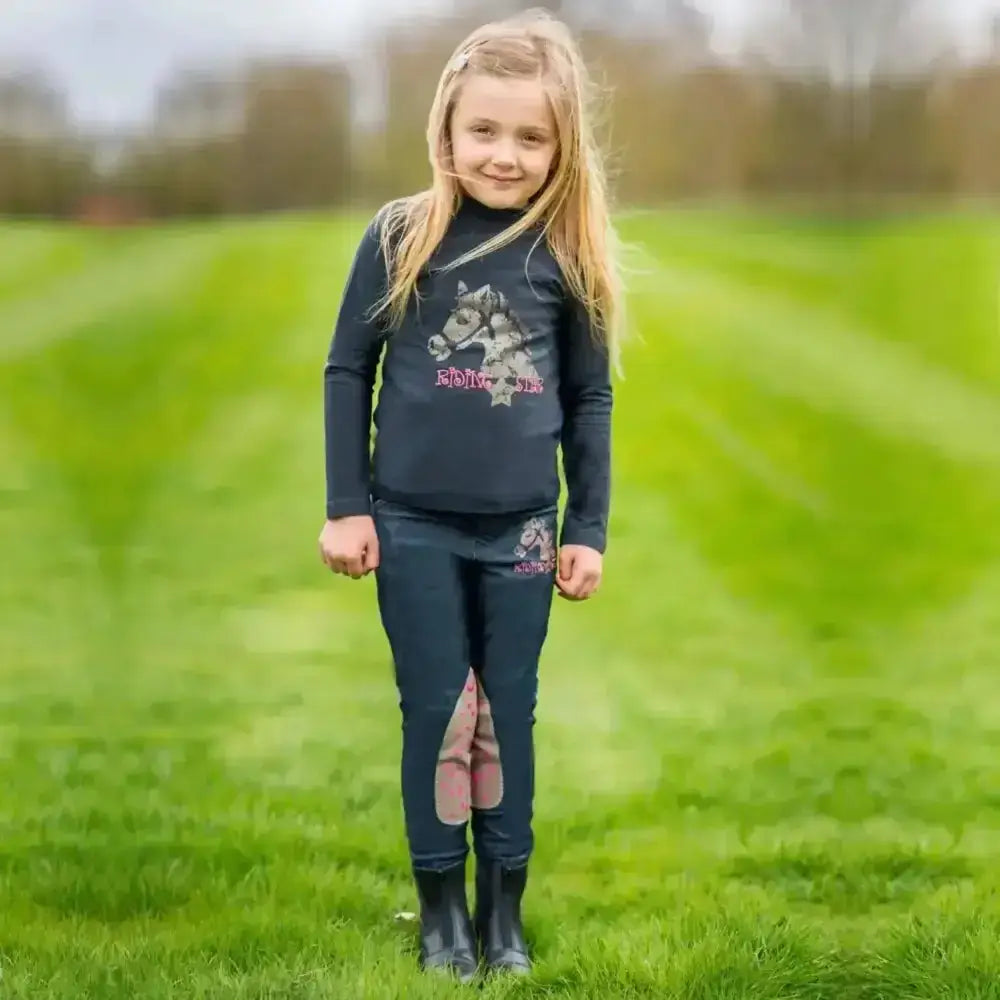 Dark blue long-sleeved turtleneck top with wolf graphic and pink text styled with riding star denim jodhpurs with reinforced alos knees