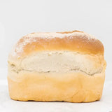 Golden brown round white bread loaf with a dusting of flour and a soft airy interior perfect for sandwiches