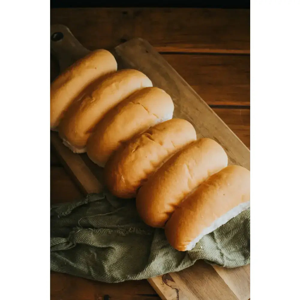 Golden-brown ryders bakery white finger rolls with soft texture on wooden board perfect for sandwiches or sides