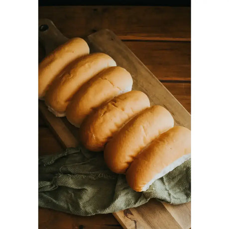 Golden-brown ryders bakery white finger rolls with soft texture on wooden board perfect for sandwiches or sides