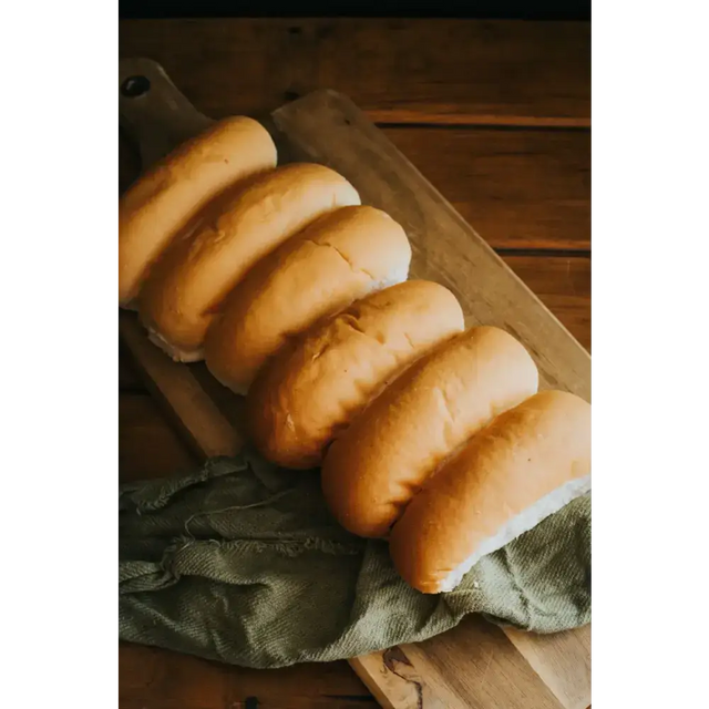 Golden-brown ryders bakery white finger rolls with soft texture on wooden board perfect for sandwiches or sides