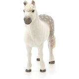 A white and gray spotted schleich welsh pony stallion figurine with detailed face on plain background