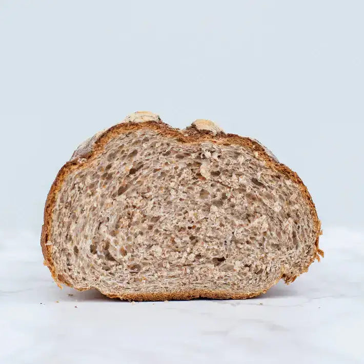 A freshly sliced sesame seed granary bloomer loaf of bread with a golden brown crust and airy speckled interior