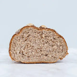 A freshly sliced sesame seed granary bloomer loaf of bread with a golden brown crust and airy speckled interior