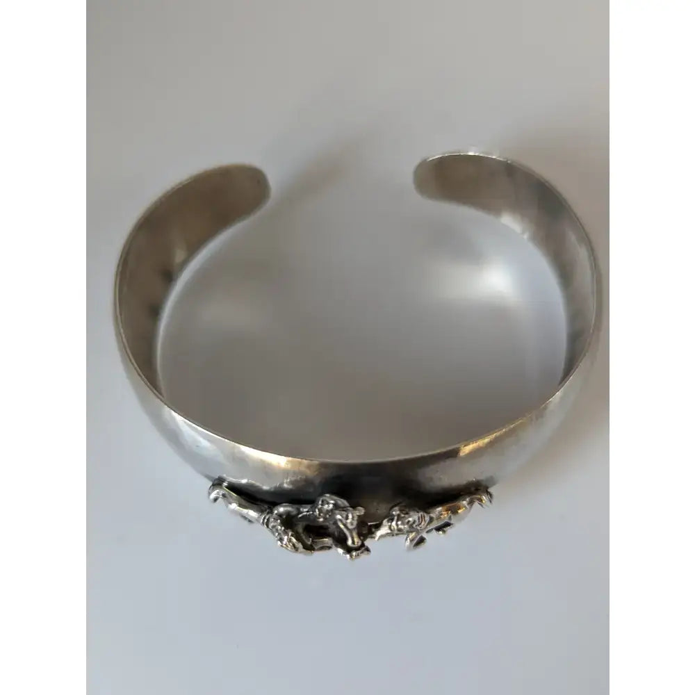 Silver steed herd bangle featuring a silver cuff with hammered finish and detailed 3d sculpted horse figures