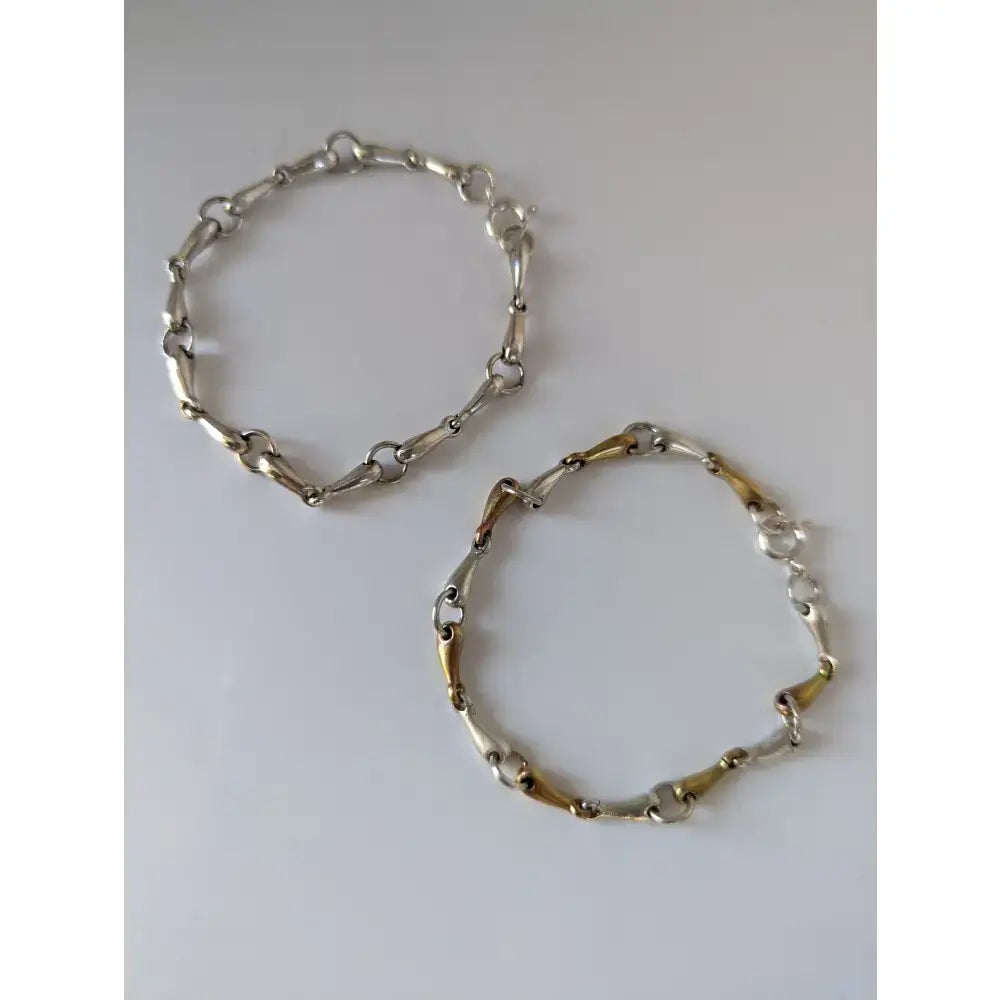 Two silver and gold-toned chain bracelets from silver steed featuring a delicate silver snaffles bracelet design