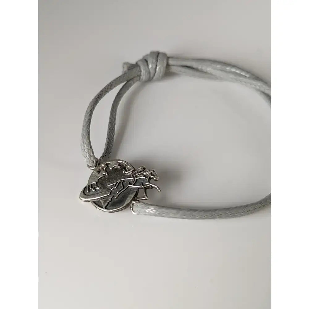 Silver steed world bracelet with silver charm of a horse rider around the globe on a braided gray cord equestrian style