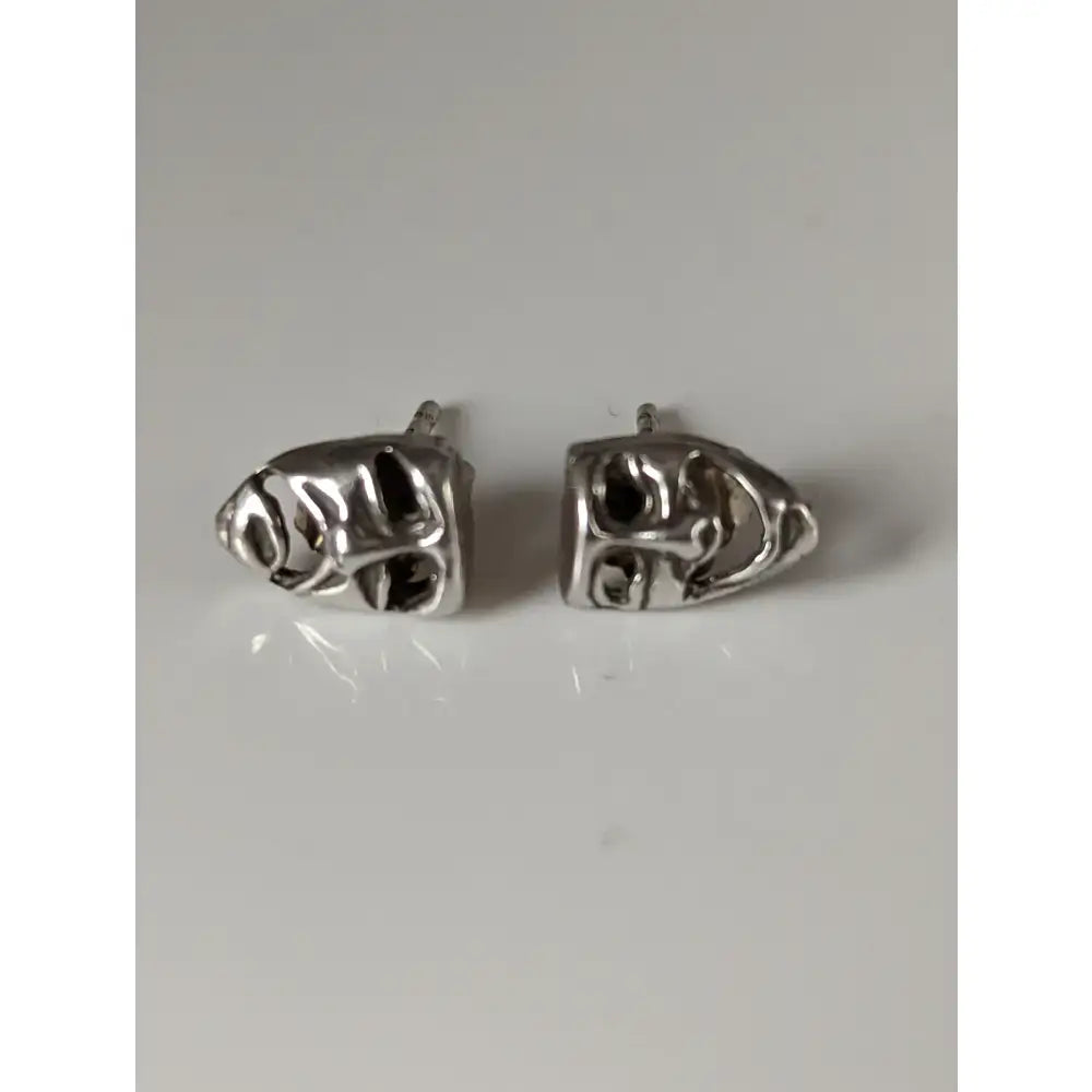 Silver steed comedy tragedy masks stud earrings featuring silver skull-shaped studs with intricate engraved details