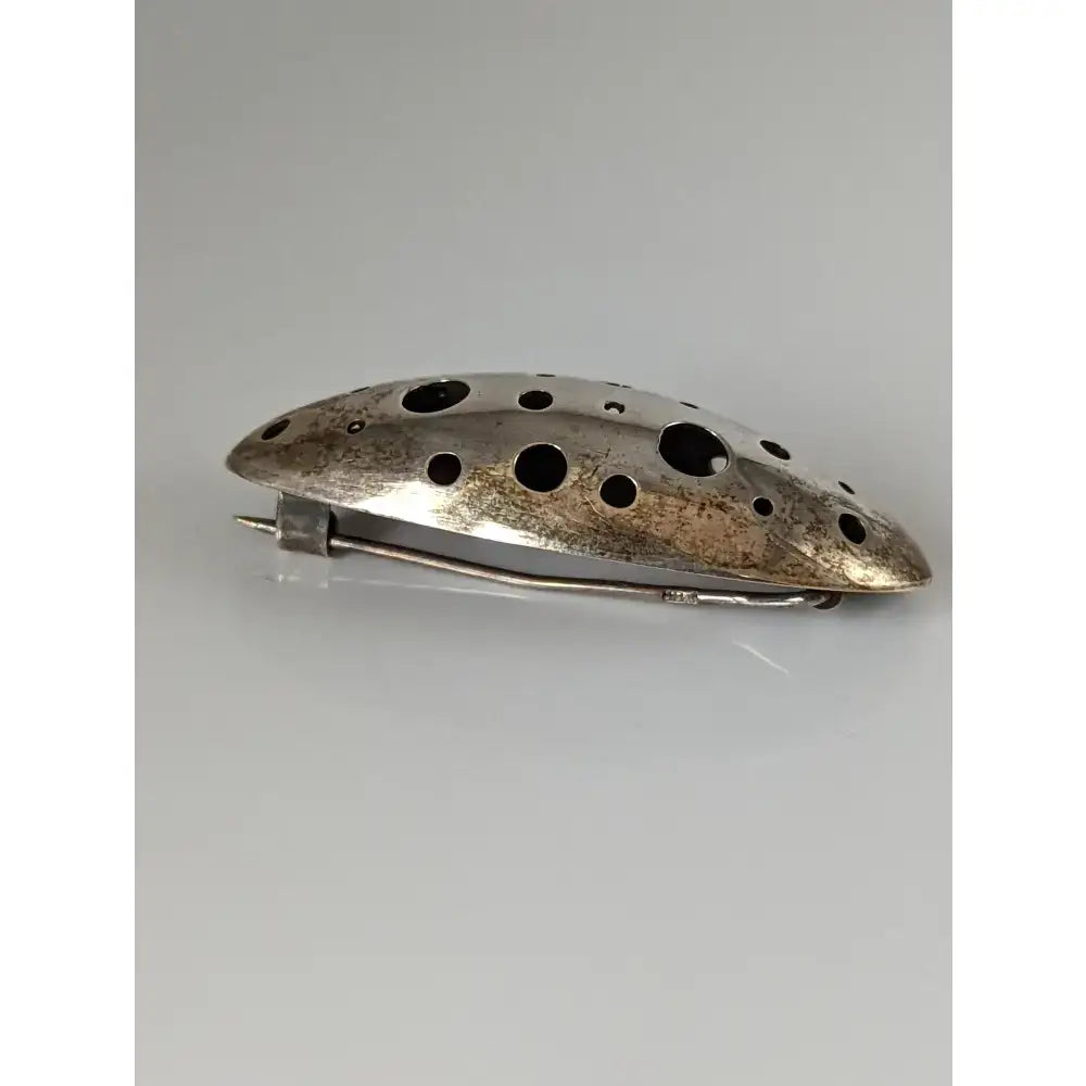 Silver steed coral silver brooch with a sleek elongated oval shape and circular cutouts in silver tone metal