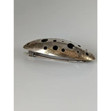Silver steed coral silver brooch with a sleek elongated oval shape and circular cutouts in silver tone metal