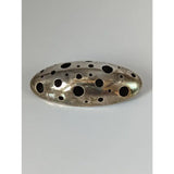 Silver steed coral silver brooch with oval textured metal design and multiple circular holes in silver tone