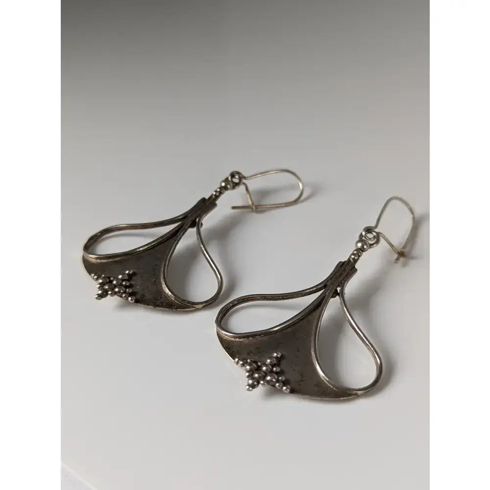 Silver steed crest dropped earrings featuring silver teardrop shape with hammered texture and bead clusters at bottom