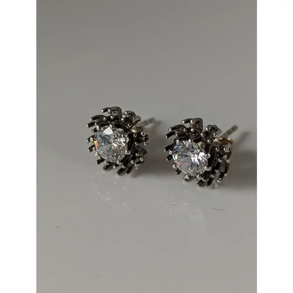 Black spider-themed sunflower stud earrings with silver steed crystal centers and detailed metallic design
