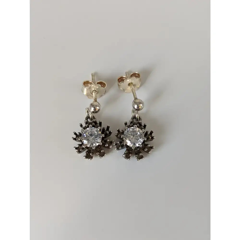 Silver steed dangling crystal sunflower stud earrings with clear central gemstone and dark spiky metal petals