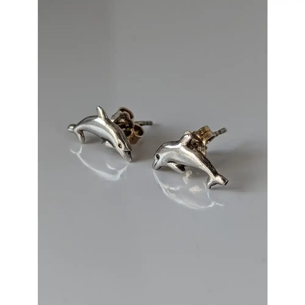 Silver steed dolphin stud earrings with polished metallic finish and detailed sculpting in silver dolphin shape