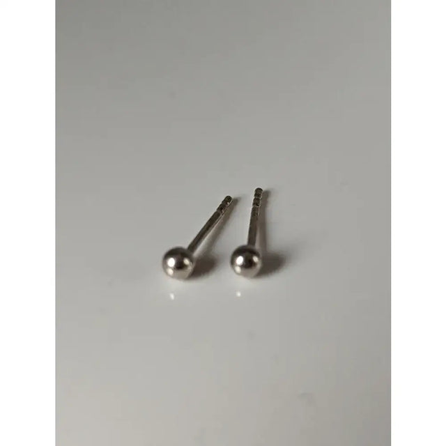 A pair of silver steed ball stud earrings with a sleek polished metallic finish and unique shape