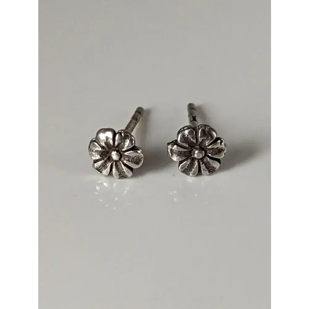 Silver steed flower stud earrings with detailed petals and a small central gem in a shiny silver finish