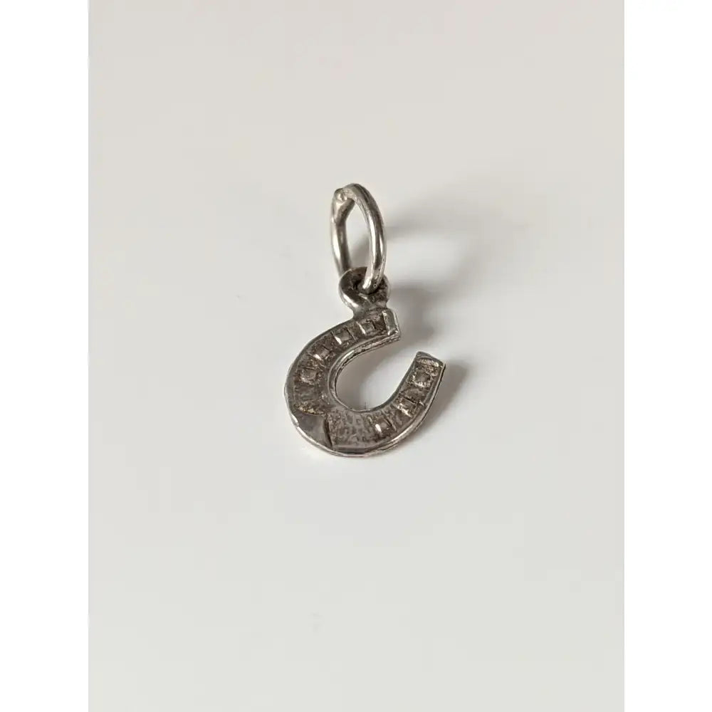 Silver steed pendant featuring a silver horseshoe silver pendant with clear stones along its curved edge