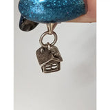 Silver charm shaped like a house with textured roof and window details from the silver steed house equestrian jewelry line